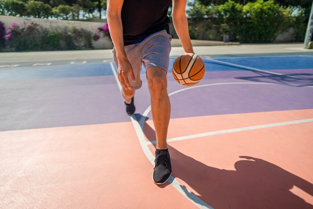 Legs of a professional basketball player dribbling the ball on the basketball field
